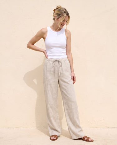 The Loelia Linen Pants in natural linen — wide-leg linen trousers, front view with hand on hip on model