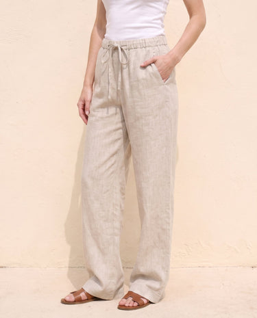 The Loelia Linen Pants in natural linen — wide-leg linen trousers, front view tying the drawstring on model