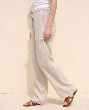 The Loelia Linen Pants in natural linen — wide-leg linen trousers, side view on model