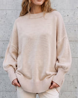 The Lorna knit pullover in beige — front view with hands in pockets on model