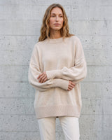 The Lorna knit pullover in beige — front view with arms crossed on model