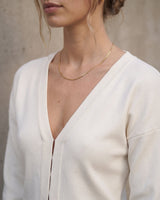 The Maisonette Cardigan in white — close-up of the V-neckline and front placket