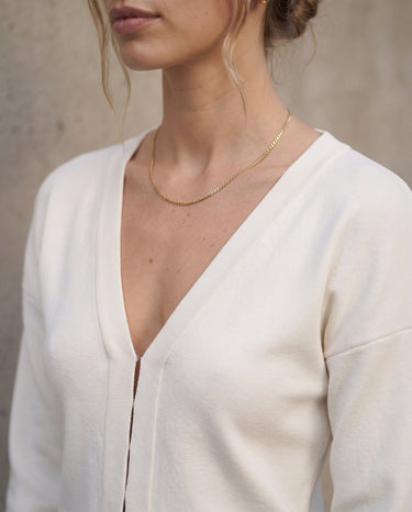 The Maisonette Cardigan in white — close-up of the V-neckline and front placket