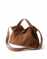The Manon Suede Tote in tan, three-quarter studio view showing the slouched suede body, leather top handles and adjustable crossbody strap