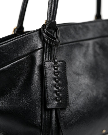 Close-up of the Marais Carryall's whipstitched leather tag and tassel detail in black