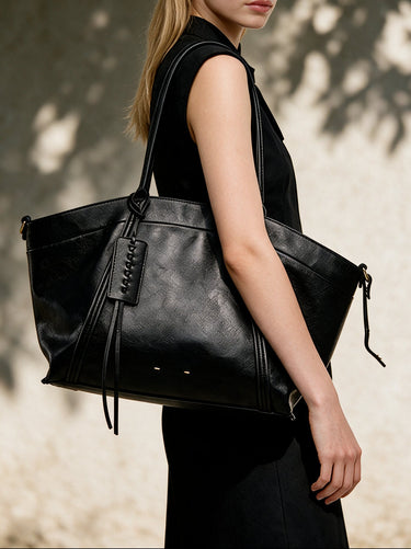 The Marais Carryall in black carried on the shoulder with a black sleeveless dress in sunlight
