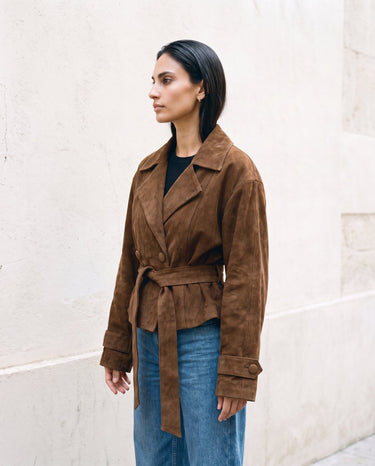 Three-quarter side view of the dark brown Margot Tie-waist Coat over blue jeans
