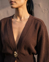The Marley Cardigan in brown — close-up of the V-neckline and gold button