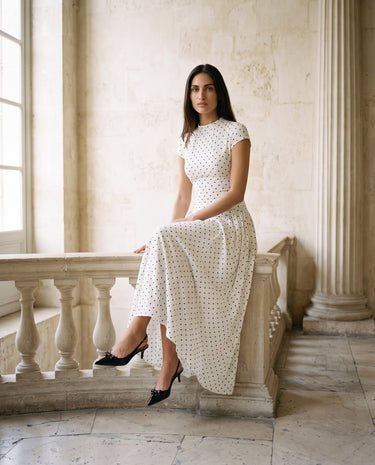 The Maura Polka Dot Dress in cream — polka dot maxi dress, seated view on model