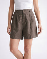 The Mauria Linen Shorts in cocoa — high-waisted pleated linen shorts, front view on model