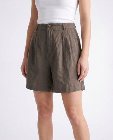 The Mauria Linen Shorts in cocoa — pleated linen shorts, side view on model