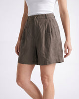 The Mauria Linen Shorts in cocoa — pleated linen shorts, walking side view on model
