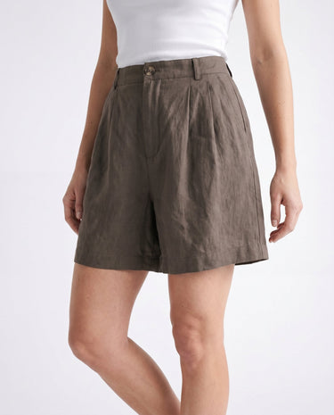 The Mauria Linen Shorts in cocoa — pleated linen shorts, walking side view on model