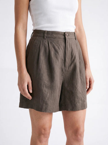The Mauria Linen Shorts in cocoa — close-up of pleated high-rise waist on model