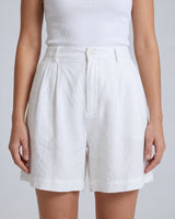 The Mauria Linen Shorts in white — high-waisted pleated linen shorts, front view on model