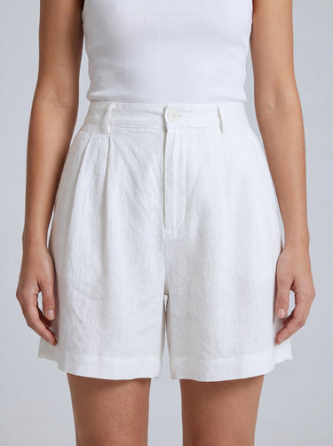 The Mauria Linen Shorts in white — high-waisted pleated linen shorts, front view on model