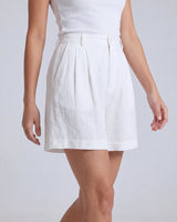 The Mauria Linen Shorts in white — pleated linen shorts, walking view on model