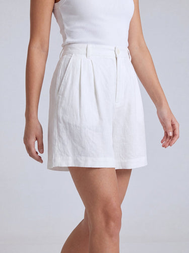 The Mauria Linen Shorts in white — pleated linen shorts, walking view on model