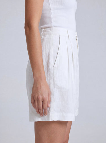 The Mauria Linen Shorts in white — pleated linen shorts, side view on model