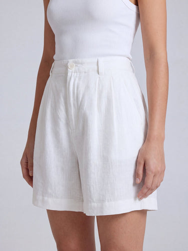 The Mauria Linen Shorts in white — pleated linen shorts, three-quarter view on model