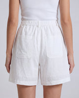 The Mauria Linen Shorts in white — high-waisted pleated linen shorts, back view on model