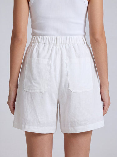 The Mauria Linen Shorts in white — high-waisted pleated linen shorts, back view on model