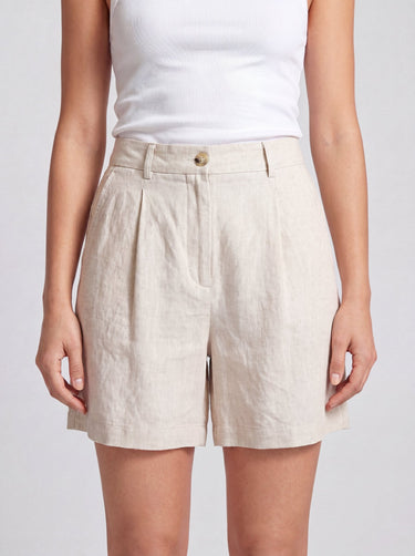 The Mauria Linen Shorts in oat — high-waisted pleated linen shorts, front view on model