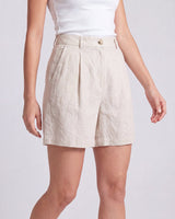 The Mauria Linen Shorts in oat — pleated linen shorts, walking view on model
