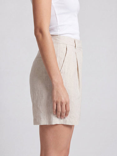 The Mauria Linen Shorts in oat — pleated linen shorts, side view on model