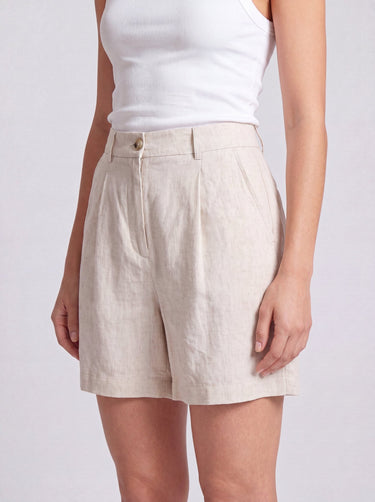 The Mauria Linen Shorts in oat — pleated linen shorts, three-quarter view on model