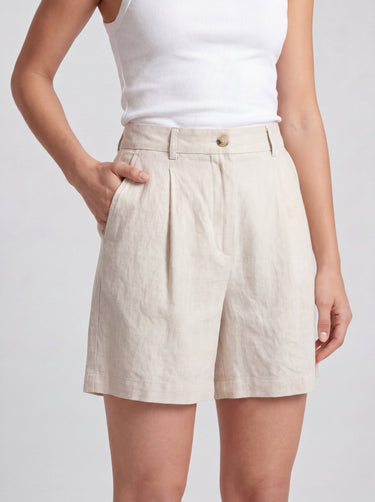 The Mauria Linen Shorts in oat — pleated linen shorts with side pockets, hand-in-pocket view on model