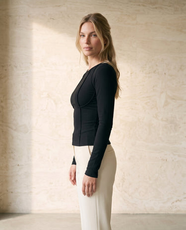 The Noa Piped Long Sleeve in black — slim ribbed long-sleeve top, side view on model