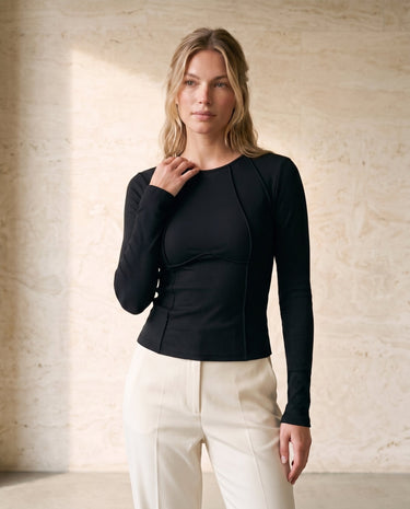 The Noa Piped Long Sleeve in black — slim ribbed long-sleeve top, front three-quarter view on model