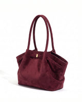 The Odette Suede Tote in wine red, three-quarter studio view on a pure white background with gold-tone keeper