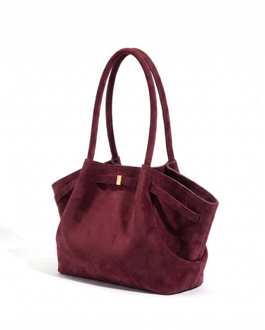 The Odette Suede Tote in wine red, three-quarter studio view on a pure white background with gold-tone keeper