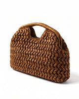 The Ravello Woven Clutch in turmeric, three-quarter studio view showing the woven body and top handle cut-out