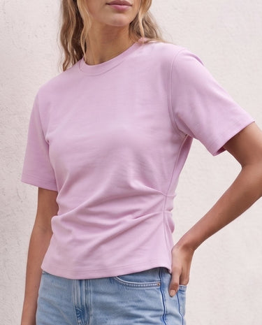 The Riela Tee in pink — short-sleeve tee, front view with hand on hip on model