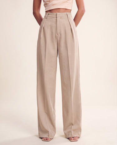 The Riviera Tailored Pants in beige — wide-leg tailored pants, front view on model