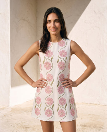 The Rosalie Floral Dress in pink — sleeveless floral mini dress, front view on model with hands on hips