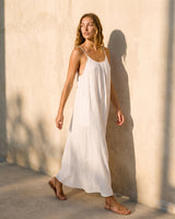 The Rylie Dress in white — flowing maxi dress, walking side view on model