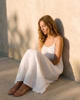 The Rylie Dress in white — flowing maxi dress, seated view on model