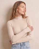 The Sable mock neck top in beige — front three-quarter view with arms crossed on model