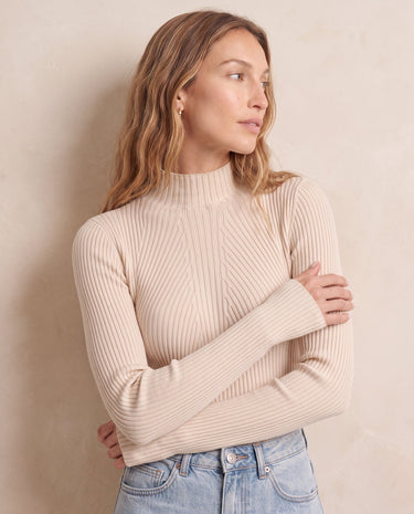 The Sable mock neck top in beige — front three-quarter view with arms crossed on model
