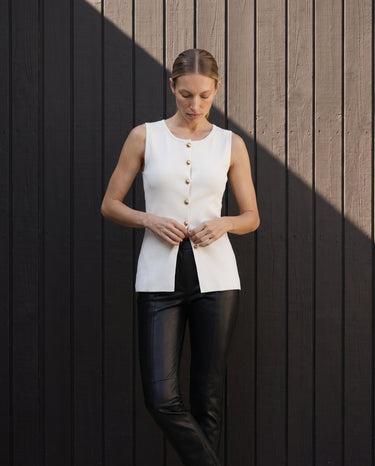 Model buttoning the white sleeveless vest, full front view – Moriel Heritage