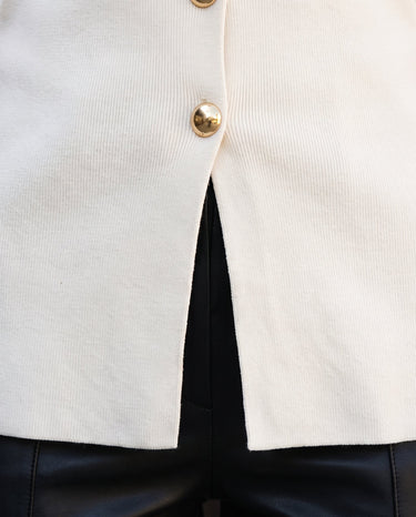 Close-up of the vest's gold button and front hem split – Moriel Heritage