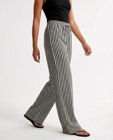 The Seville Stripe Drawstring Pant in black stripe — striped wide-leg trousers, side view on model