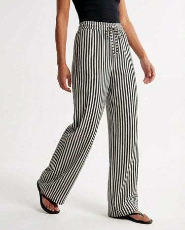 The Seville Stripe Drawstring Pant in black stripe — striped wide-leg trousers, three-quarter view on model