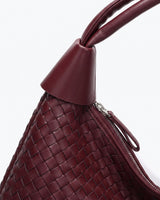 Close-up of the Siren Woven Bag's knotted leather strap detail and basketweave texture in burgundy