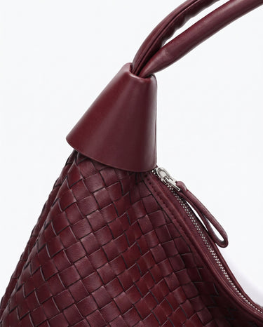 Close-up of the Siren Woven Bag's knotted leather strap detail and basketweave texture in burgundy