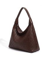 The Siren Woven Bag in brown, three-quarter studio view showing the woven body and knotted strap